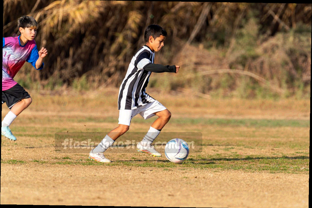 编辑在双屏工作站前比对赛事资料，桌面摊着赛程表与批注稿